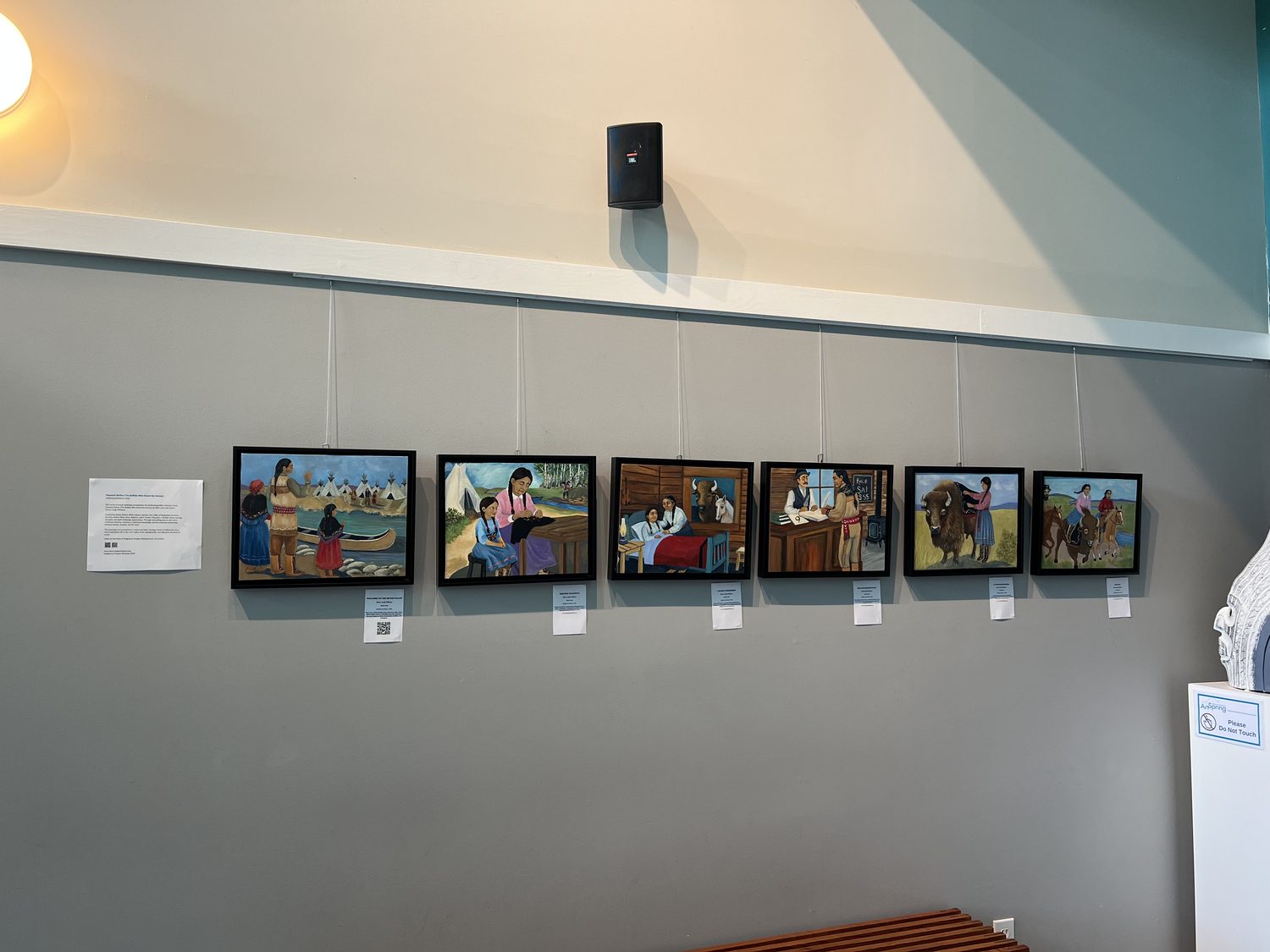 A row of framed story paintings on a gallery wall