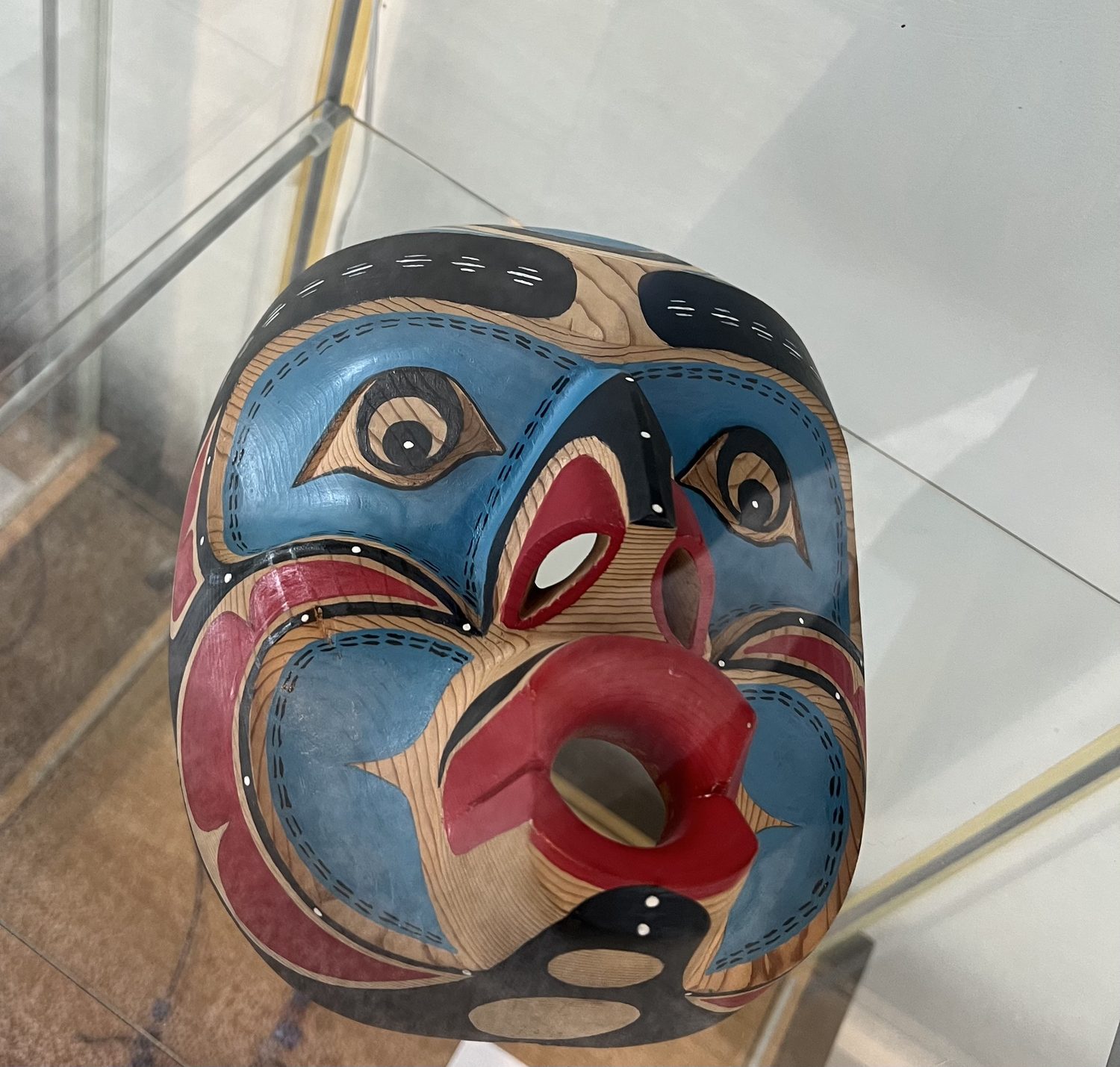 Carved and painted cedar mask in a display case
