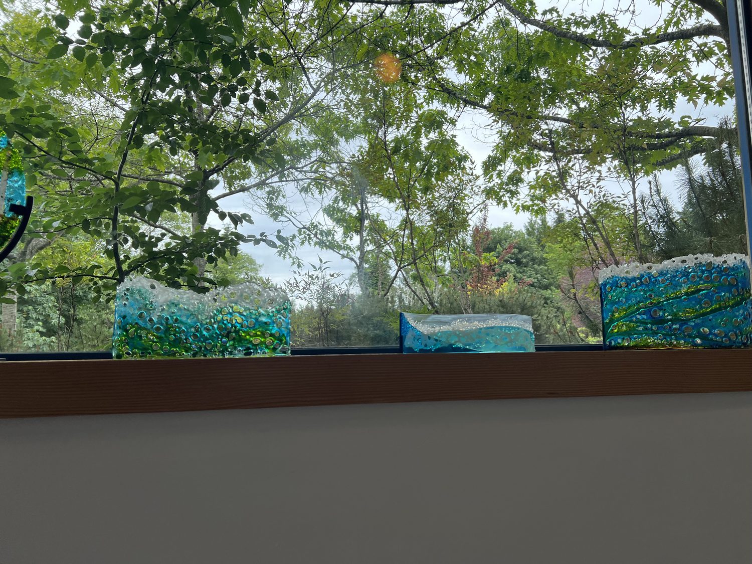Blue and green fused-glass wave pieces on a sill