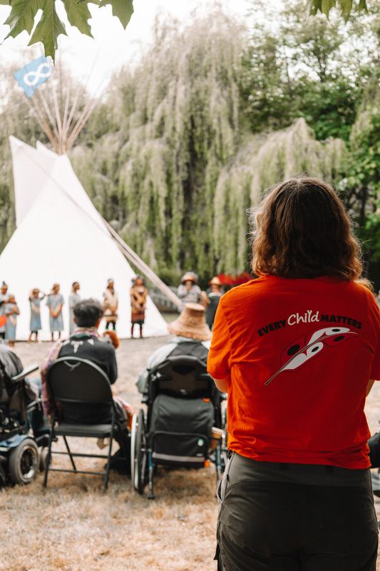 A community member in an Every Child Matters shirt witnesses the ceremony