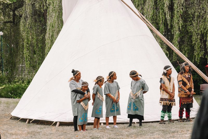 Community members of all ages dance together in the meadow