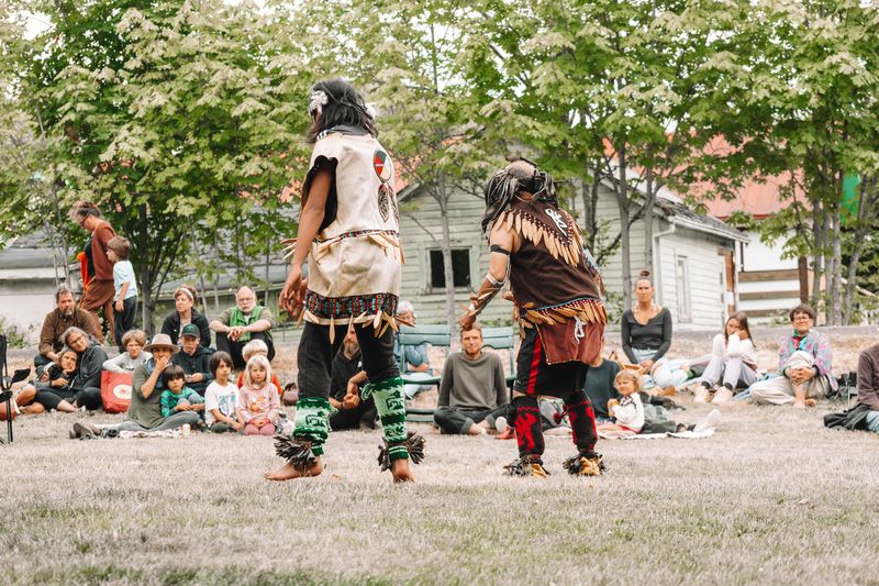 A wide view of the audience watching dancers in front of the tipi