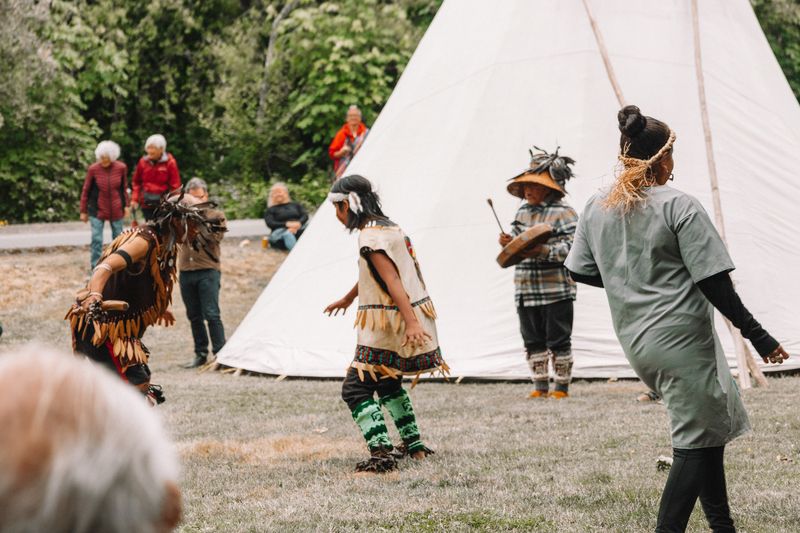 The wider gathering with regalia dancers and audience members in a circle