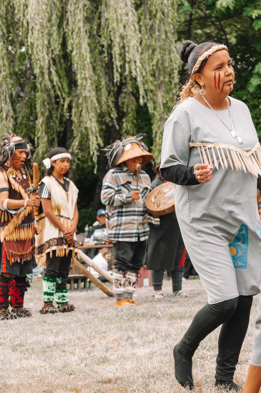 Mother and young dancers in grey regalia clapping in unison