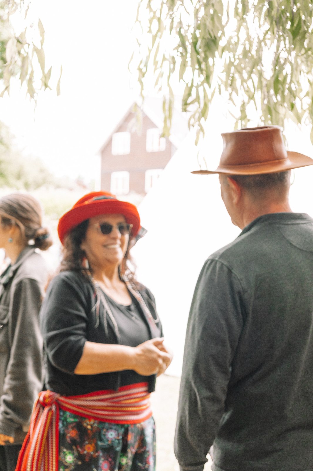 A community member in a Métis sash and red hat at IPW 2025