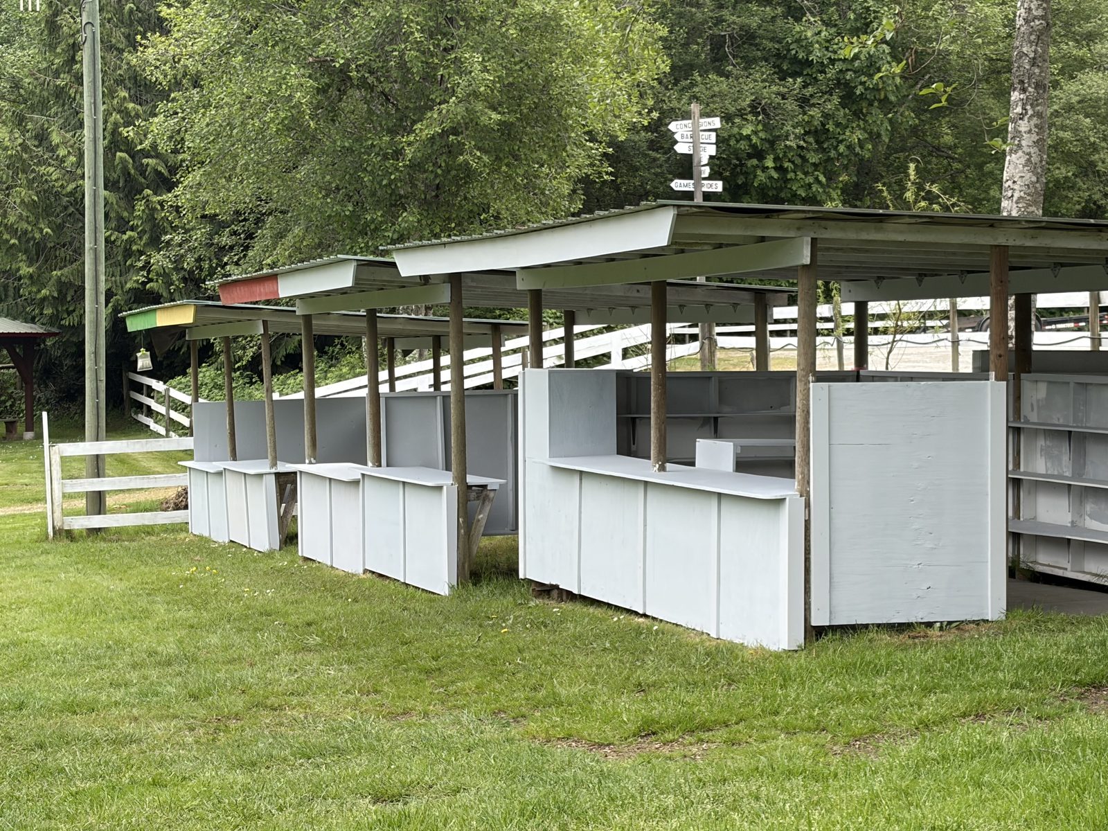 A row of white fixture stalls at the Farmers Institute — four regular stalls and one large stall with shelving